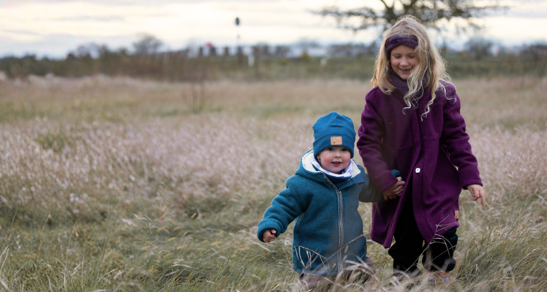 Wollwalkjacken für Kinder, zwei Kinder auf einer Herbstwiese
